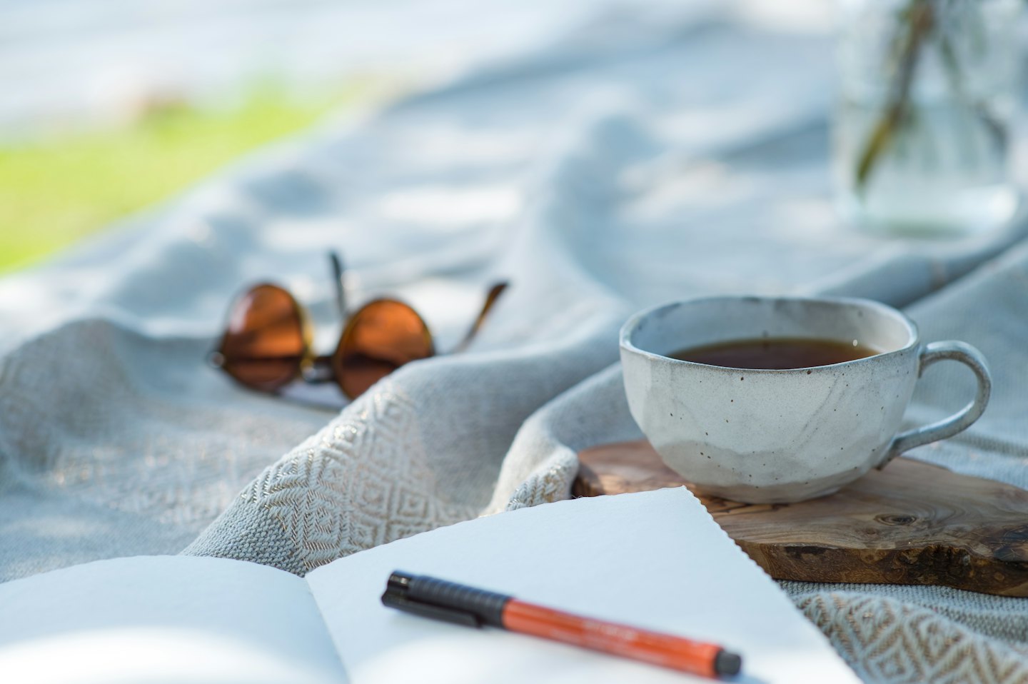 Taza de té y cuaderno sobre una manta acogedora al aire libre.